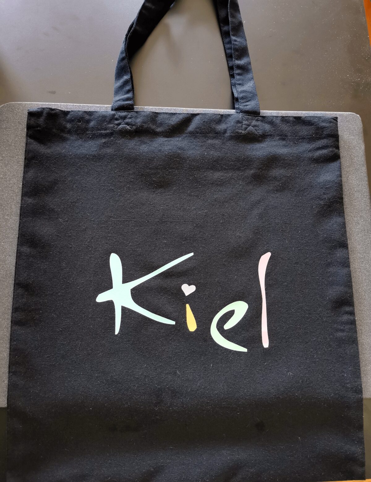 Bunte Tragetasche mit der Aufschrift "Kid" auf schwarzem Hintergrund, umweltfreundliche Einkaufstasche für Kinder, nachhaltiges Shopping Zubehör.